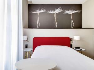 a bedroom with a white bed with a red head board at Ibis Styles Toulouse Capitole in Toulouse