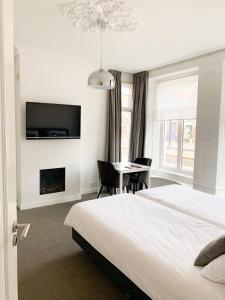 a bedroom with a bed and a table and a tv at b&b het Herenhuys aan de historische gracht van Kollum in Kollum