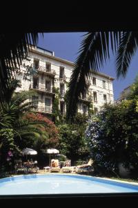 ein großes Gebäude mit einem Pool vor einem Gebäude in der Unterkunft Le Windsor, Jungle Art Hotel in Nizza