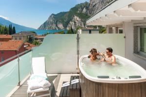 Ein Mann und eine Frau sitzen in einer Badewanne auf einem Balkon in der Unterkunft Parc Hotel Flora in Riva del Garda
