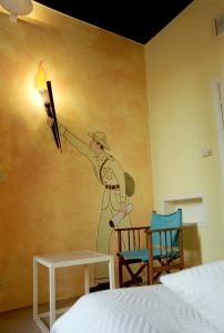 a bedroom with a painting of a man with a gun on the wall at Le Windsor, Jungle Art Hotel in Nice