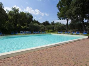 une grande piscine avec des chaises et des arbres bleus dans l'établissement Antico Borgo Poggiarello, à Monteriggioni