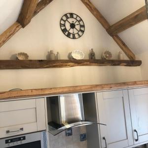 a clock on the wall above a kitchen counter at The Tack Room Cottage in Blandford Forum