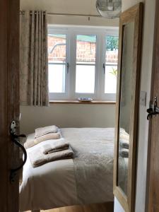 a bedroom with a bed with pillows and two windows at The Tack Room Cottage in Blandford Forum