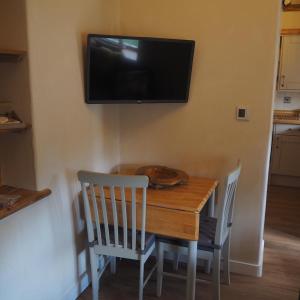 a dining room table with chairs and a television on the wall at The Tack Room Cottage in Blandford Forum