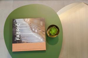 a book and a plant on a green wall at 36 Geula - By Beach Apartments TLV in Tel Aviv