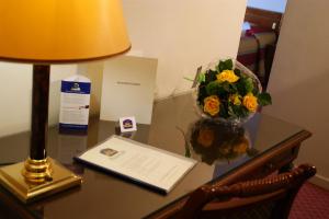 a desk with a laptop and a vase of flowers at Best Western Plus Park Hotel Brussels in Brussels