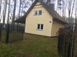 una pequeña casa amarilla con una valla negra en Kurort Mirowice, en Mirowice