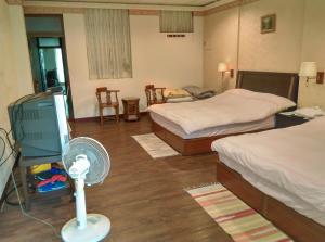 a hotel room with two beds and a fan at Coffee Street Homestay in Gukeng