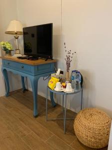 a blue desk with a table with a television on it at Baan Suan Krung Kao in Phra Nakhon Si Ayutthaya