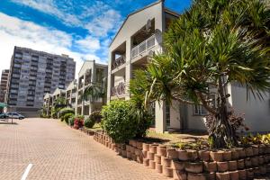 ダーバンにあるKADESE Holiday North Beach Durbanのヤシの木が立ち並ぶ白いアパートメントビル