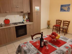 阿格里真托的住宿－terre di girgenti，厨房配有桌子,提供一瓶葡萄酒和水果