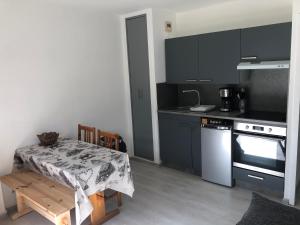 uma cozinha com armários pretos, uma mesa e um fogão em Le petit Chamois em Saint-Gervais-les-Bains