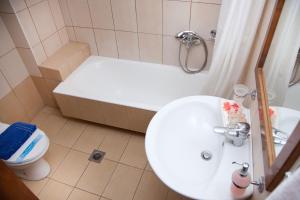 
a bathroom with a sink, toilet and bath tub at Akroyali Hotel & Villas in Áyios Andréas Messinias
