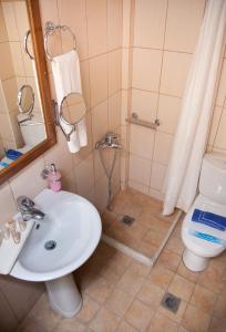 a bathroom with a sink and a shower with a toilet at Akroyali Hotel & Villas in Agios Andreas