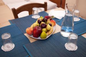 a table with a bowl of fruit on a plate at Akroyali Hotel & Villas in Áyios Andréas Messinias