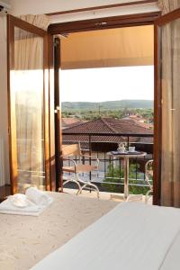 Akroyali Hotel & Villas في أيوس أندرياس ميسينياس: غرفة نوم مع سرير وبلكونة مع طاولة