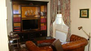 a living room with a leather couch and a television at CASA RURAL PIEDRAHÍTA ( ART DÉCO ) in Piedrahita