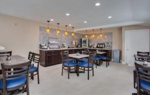 a dining room with tables and chairs and a kitchen at SureStay Plus Hotel by Best Western Chula Vista West in Chula Vista