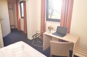 a room with a desk with a laptop on it at Best Deal Airporthotel Weeze in Weeze