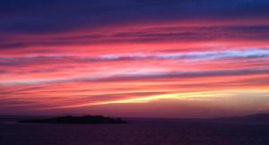 einen Sonnenuntergang über dem Meer mit einem rosa in der Unterkunft White Myth in Mykonos Stadt