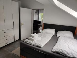 Schlafzimmer mit einem schwarzen Bett mit weißer Bettwäsche und Kissen in der Unterkunft Im Mückenberg 4 in Lahnstein