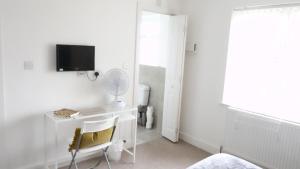 a white bedroom with a desk and a mirror at Great Airport Sleep in Harmondsworth