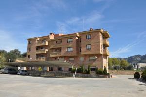 un gran edificio con un estacionamiento delante de él en Aparthotel Tres Caminos en El Grado