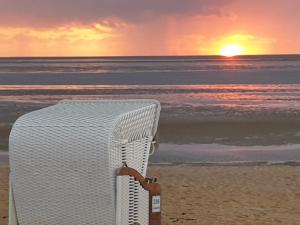a wicker chair sitting on the beach at sunset at Haus Frauenpreiss 67 in Cuxhaven