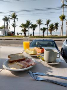 a table with a plate of food and a cup of orange juice at HOTEL ENSEADA BEIRA MAR in Guarujá