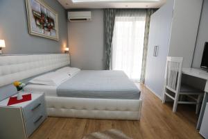 um quarto com uma cama branca e uma secretária. em Hotel Vila Verde City Center em Tirana