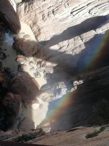 un arco iris sobre un río con rocas y agua en La Casita de Madera, en Ardales