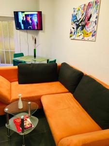 ein Wohnzimmer mit einem orangenen Sofa und einem Tisch in der Unterkunft Gästehaus Don Camillo in Ensdorf