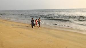 three women walking on the beach near the ocean at kannur west beach house in Kannur