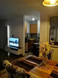 a living room with a table with a television and a kitchen at Apartman EDEN No 1 in Teslić