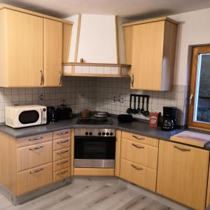 a kitchen with wooden cabinets and a microwave at Ferienhaus am Bach in Deuerling