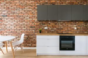 una cucina con armadietti bianchi e un muro di mattoni di Easy Apartments Wrocław a Breslavia