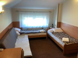 Habitación pequeña con 2 camas y ventana en Motel Orion, en Piła