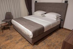 ein Schlafzimmer mit einem großen Bett mit weißer Bettwäsche und Kissen in der Unterkunft Qama Hotel in Pristina
