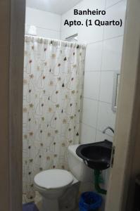 a bathroom with a toilet and a shower curtain at Apto Praia de Setiba in Una