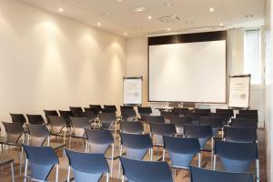 une salle de conférence avec des chaises et un écran de projection dans l'établissement Campanile Paris Porte d'Italie - Le Kremlin Bicêtre, au Kremlin-Bicêtre