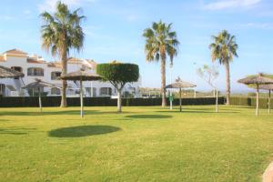 グラン・アラカントにあるApartamento CasaTuris Urb.Altomar Gran Alacant GA101の建物前のヤシの木と傘が並ぶ公園