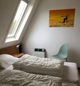 a bedroom with a bed and a chair and a window at Appartement Waddengeluk Resort Amelander Kaap! in Hollum