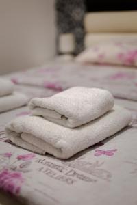 four white towels are stacked on a bed at Apartments Belville in Belgrade