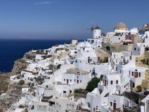 eine Gruppe weißer Gebäude auf einem Hügel in der Nähe des Ozeans in der Unterkunft Fotinos Houses in Oia