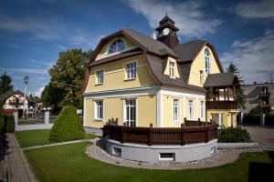 a large yellow house with a clock tower on top at Vila Demanova in Liptovský Mikuláš