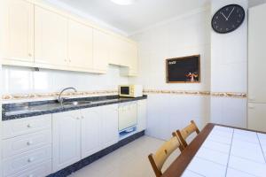a kitchen with white cabinets and a table and a clock at Modern 2bedroom Seaviews & Wifi in Araya