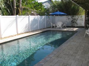 einen Pool mit einem weißen Zaun und einem Sonnenschirm in der Unterkunft Queens Gate Resort in Bradenton Beach
