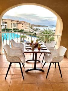 a table and chairs on a balcony with a pool at Les rivages de Coudoulière in Six-Fours-les-Plages