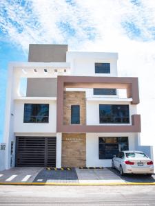 La Estancia Apartments Mazatlan في مازاتلان: منزل فيه سيارة متوقفة أمامه